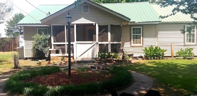 exterior space featuring a sunroom and a lawn