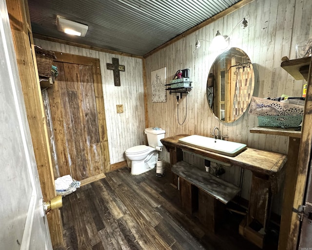 bathroom featuring hardwood / wood-style flooring, wooden walls, sink, and toilet