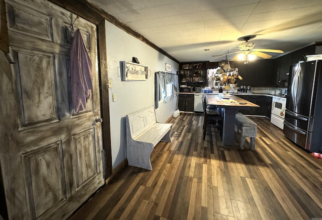 kitchen with ceiling fan, ornamental molding, dark wood-type flooring, stainless steel appliances, and a breakfast bar