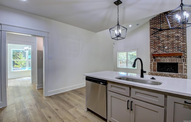 kitchen featuring pendant lighting, sink, a notable chandelier, light hardwood / wood-style flooring, and stainless steel dishwasher