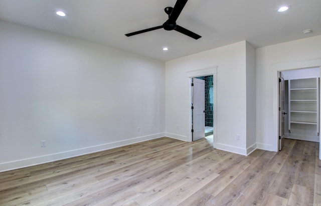 unfurnished bedroom with light hardwood / wood-style flooring, a closet, ceiling fan, and a walk in closet