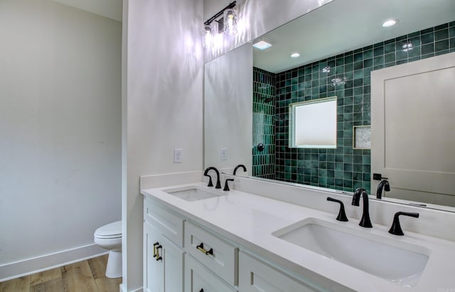 bathroom with hardwood / wood-style floors, a tile shower, vanity, and toilet