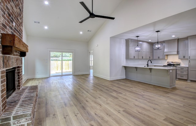 kitchen with kitchen peninsula, a kitchen bar, hanging light fixtures, a brick fireplace, and ceiling fan