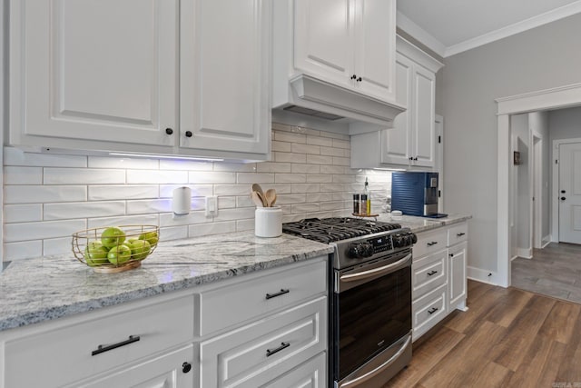 kitchen with white cabinets, ornamental molding, stainless steel gas range, hardwood / wood-style floors, and decorative backsplash