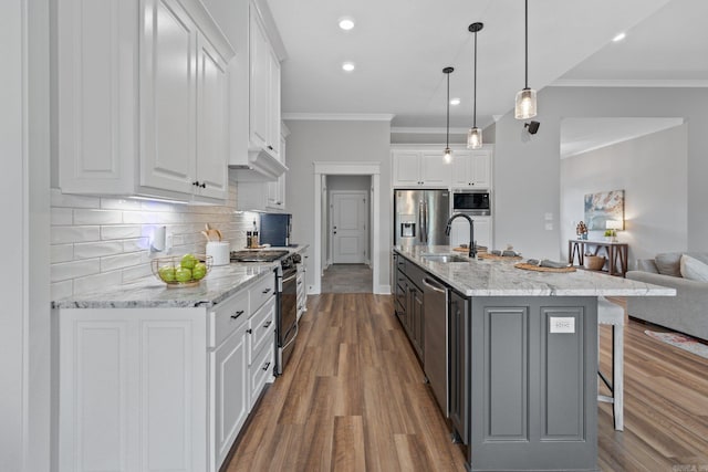 kitchen featuring sink, white cabinets, hanging light fixtures, light stone countertops, and a spacious island