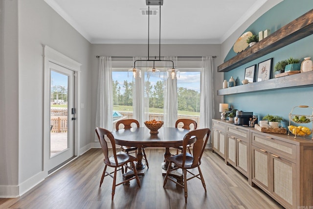 dining room with wood-type flooring, an inviting chandelier, and ornamental molding