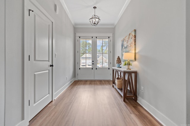 foyer featuring french doors, an inviting chandelier, light wood-type flooring, and ornamental molding