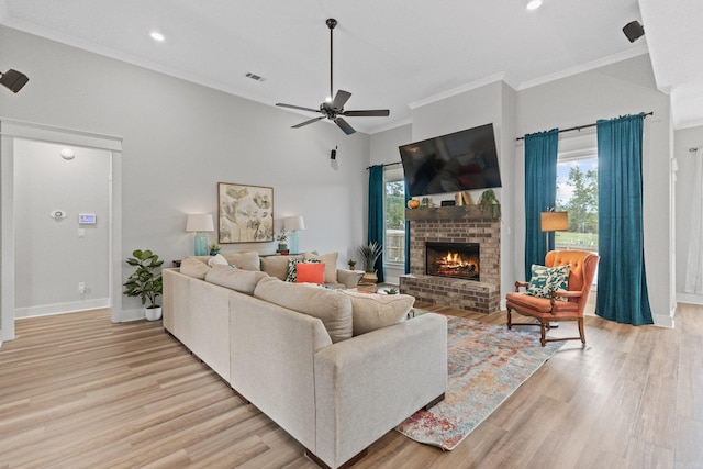 living room with ceiling fan, light hardwood / wood-style flooring, a fireplace, and a healthy amount of sunlight