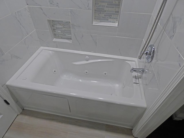 bathroom with tile walls, hardwood / wood-style flooring, and a bathtub