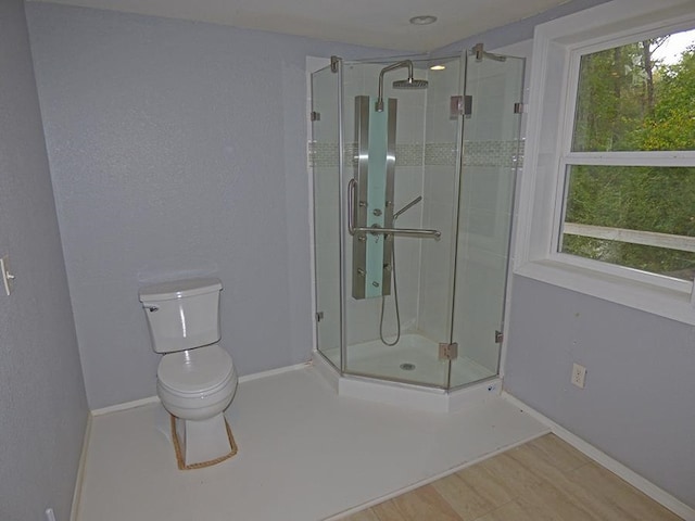 bathroom with hardwood / wood-style flooring, toilet, and an enclosed shower