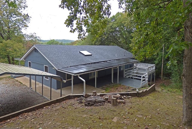 back of property with a fire pit, a wooden deck, and a patio area