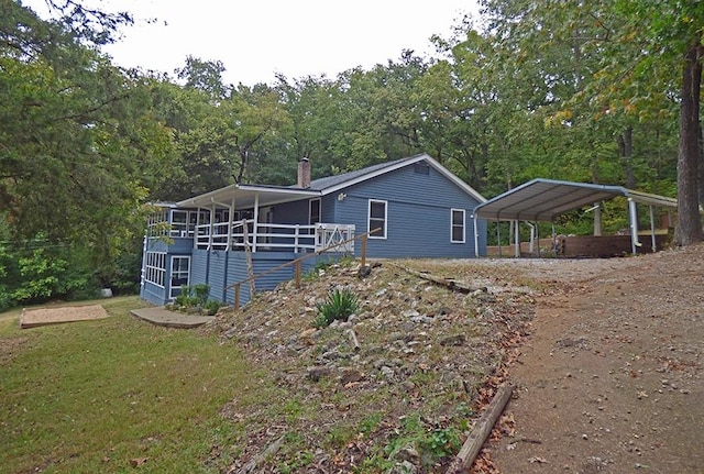 view of home's exterior featuring a carport, a yard, and a wooden deck