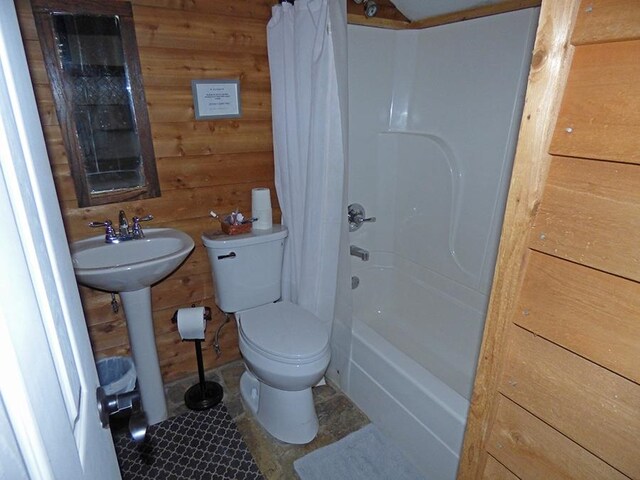 bathroom with wood walls, toilet, tile patterned floors, and shower / bath combination with curtain