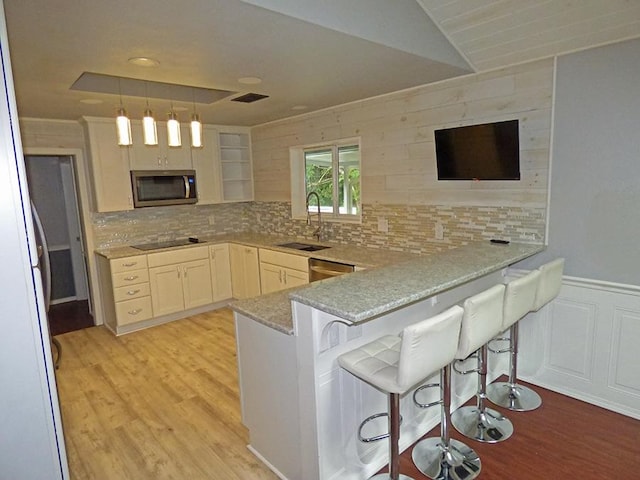 kitchen with pendant lighting, a breakfast bar area, kitchen peninsula, stainless steel appliances, and backsplash