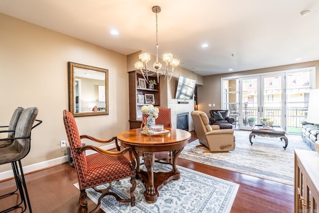 dining room with dark hardwood / wood-style floors, a chandelier, and a tiled fireplace