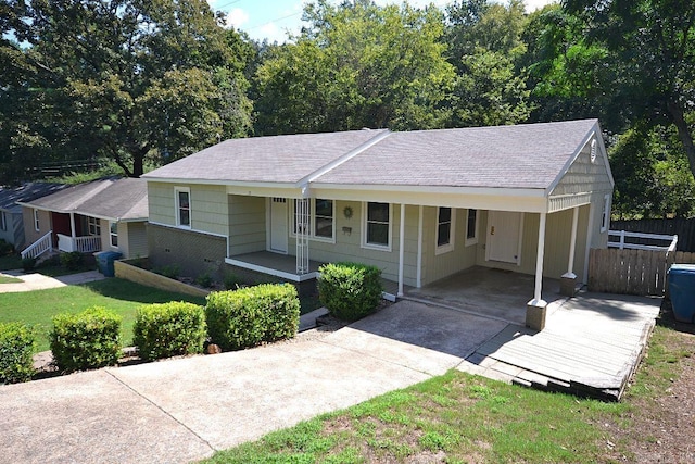 single story home with a front lawn, a carport, and a porch