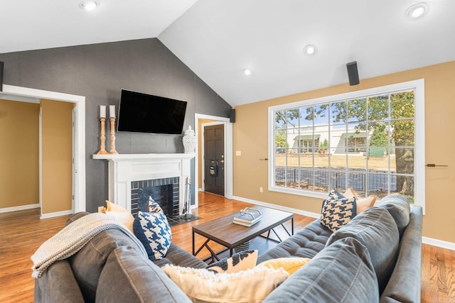 living room featuring a fireplace, vaulted ceiling, and light hardwood / wood-style flooring