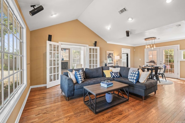 living room with french doors, ornamental molding, lofted ceiling, and light hardwood / wood-style floors