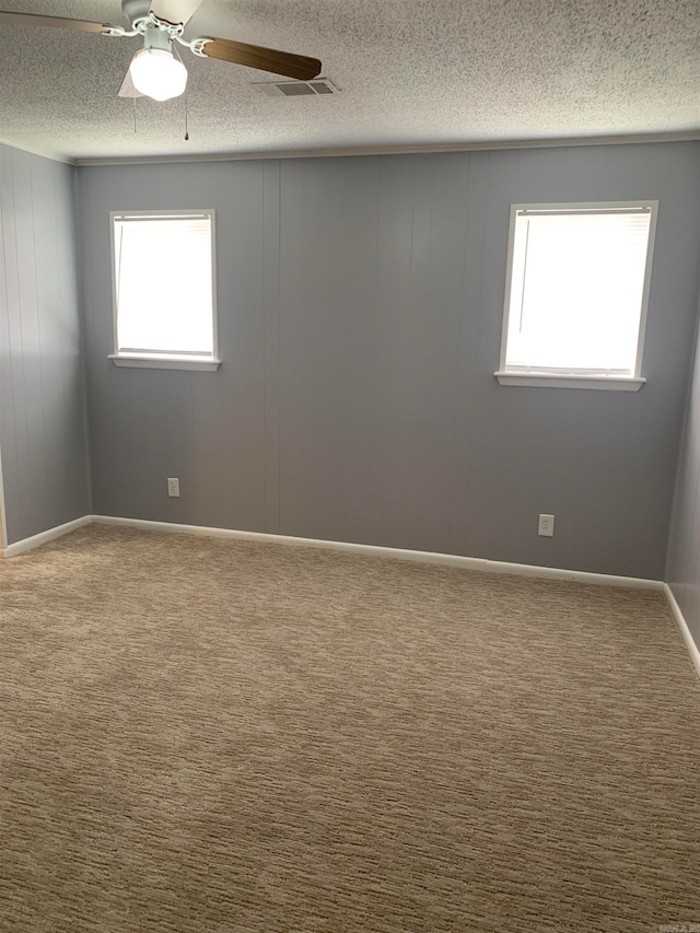 carpeted spare room featuring ceiling fan and a textured ceiling