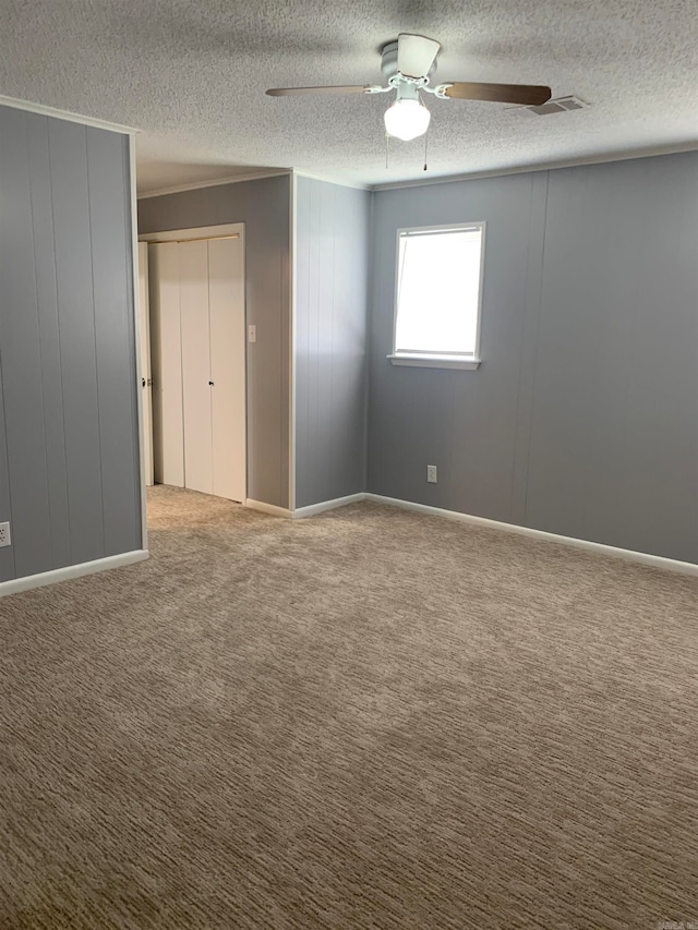 spare room featuring ornamental molding, ceiling fan, carpet flooring, and a textured ceiling