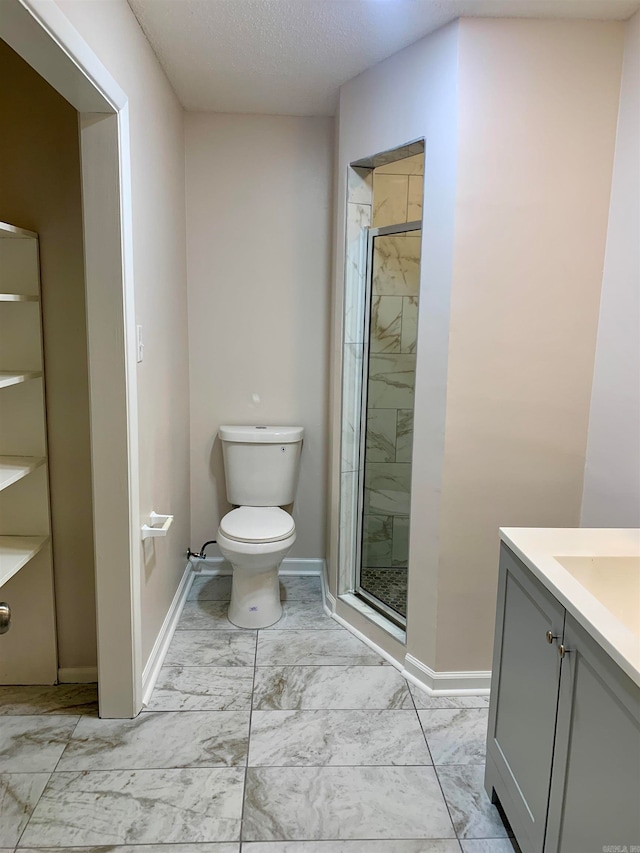 bathroom featuring vanity, a textured ceiling, a shower with shower door, and toilet