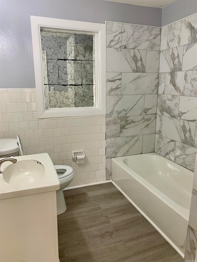 bathroom featuring tile walls, a bathing tub, toilet, and vanity