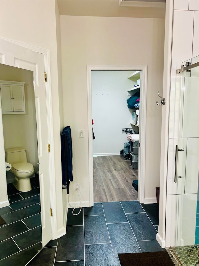 bathroom featuring a shower with door, toilet, and hardwood / wood-style flooring