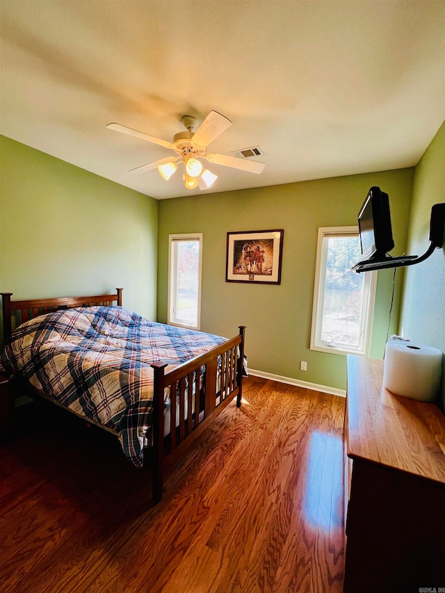 bedroom with ceiling fan, multiple windows, and hardwood / wood-style floors