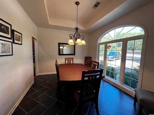 tiled dining room with a chandelier and a tray ceiling