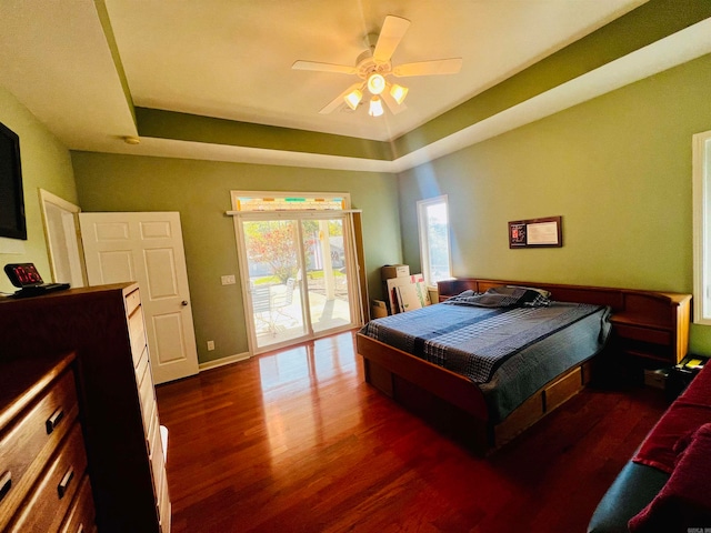 bedroom featuring access to outside, a raised ceiling, dark hardwood / wood-style floors, and ceiling fan