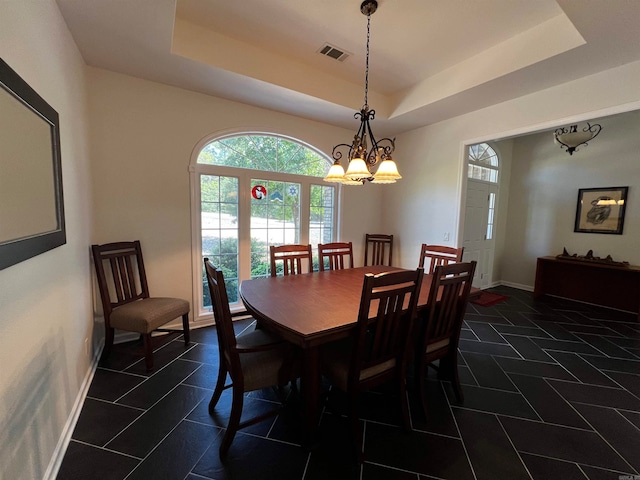 tiled dining room featuring a notable chandelier and a raised ceiling