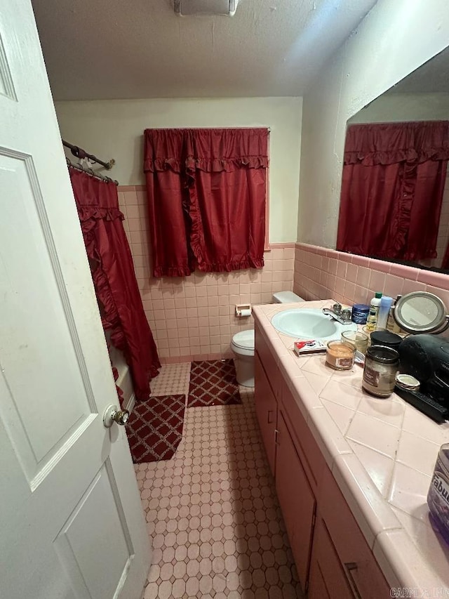 bathroom with vanity, tile walls, toilet, and curtained shower