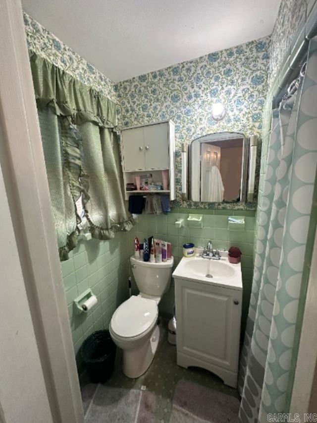 bathroom with tile walls, vanity, toilet, and a shower with shower curtain