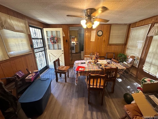 dining room featuring wooden walls, ceiling fan, and dark hardwood / wood-style flooring