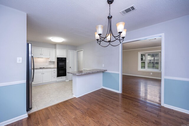 kitchen featuring sink, white cabinetry, kitchen peninsula, and black appliances