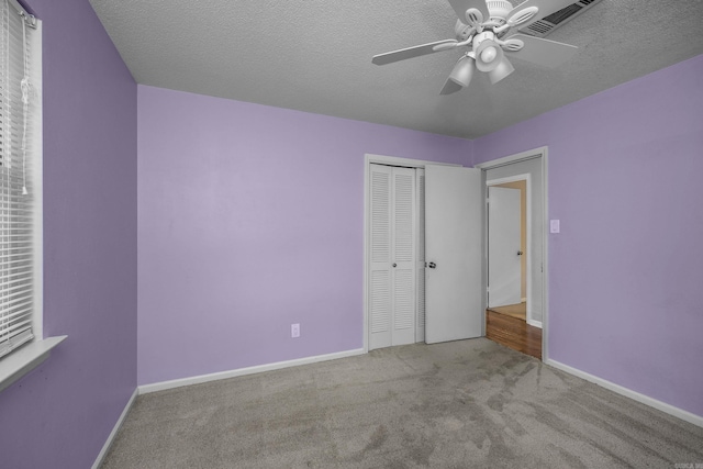 unfurnished bedroom with a textured ceiling, light carpet, ceiling fan, and a closet