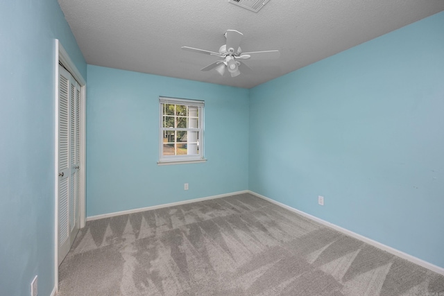 spare room featuring a textured ceiling, light carpet, and ceiling fan