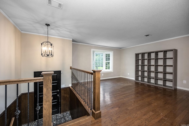 hall featuring ornamental molding, an inviting chandelier, dark hardwood / wood-style flooring, and a textured ceiling