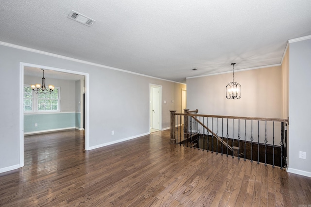 spare room with an inviting chandelier, crown molding, dark wood-type flooring, and a textured ceiling