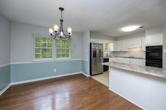 kitchen featuring white cabinets, black appliances, dark wood-type flooring, and a healthy amount of sunlight