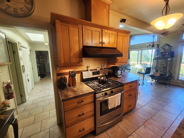 kitchen with decorative backsplash, stainless steel gas range, decorative light fixtures, and light tile patterned floors