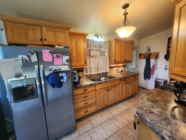 kitchen with light tile patterned flooring, hanging light fixtures, stainless steel fridge with ice dispenser, and sink