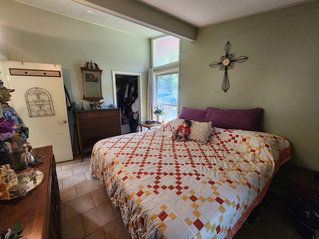 tiled bedroom featuring beam ceiling and a spacious closet