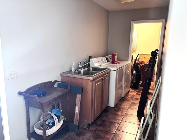 clothes washing area featuring sink, washing machine and clothes dryer, and cabinets