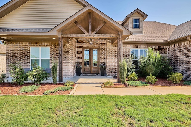 view of exterior entry with a lawn and french doors