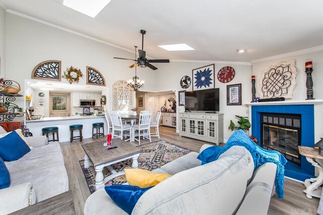 living room with light wood-type flooring, a tile fireplace, ornamental molding, and ceiling fan