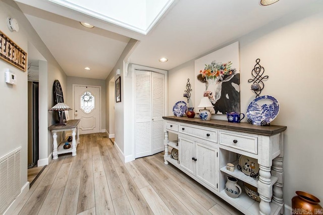 hall featuring light hardwood / wood-style floors and a skylight