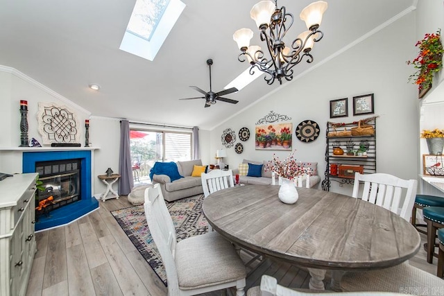 dining area with ceiling fan with notable chandelier, vaulted ceiling, light hardwood / wood-style flooring, and ornamental molding