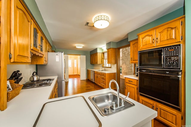 kitchen with black appliances, kitchen peninsula, sink, and hardwood / wood-style flooring