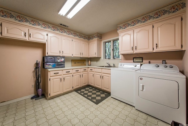 laundry room with separate washer and dryer, cabinets, sink, and a textured ceiling